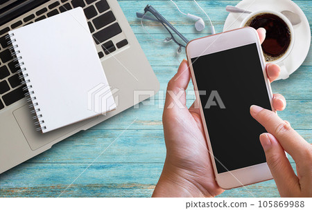 Smart phone in female hand with office desk 105869988