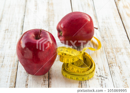 Red apple and yellow tape measure on a wooden table 105869995