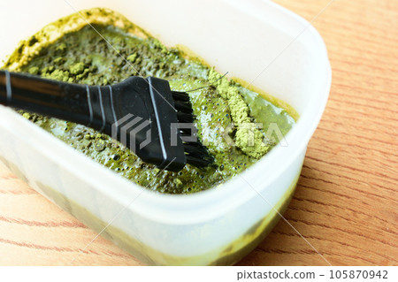 Mix henna powder for hair dye in a container with a brush 105870942