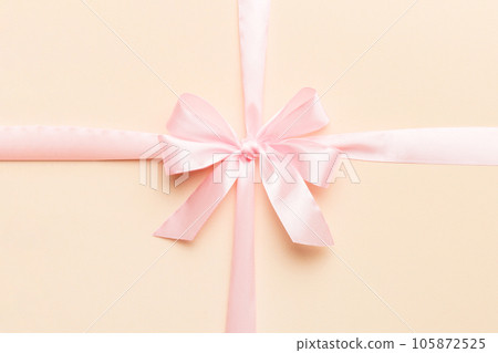 Top view of purple ribbon rolled and pink bow isolated on colored background. Flat lay with copy space 105872525