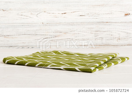 top view with green kitchen napkin isolated on table background. Folded cloth for mockup with copy space, Flat lay. Minimal style top view with green kitchen napkin isolated on table background. Folded cloth for mockup with copy space, Flat lay. Minimal style 105872724