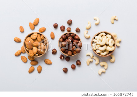 Assortment of nuts in wooden bowl on colored table. Cashew, hazelnuts, walnuts, almonds. Mix of nuts Top view with copy space Assortment of nuts in wooden bowl on colored table. Cashew, hazelnuts, walnuts, almonds. Mix of nuts Top view with copy space 105872745