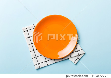 Top view on colored background empty round red plate on tablecloth for food. Empty dish on napkin with space for your design Top view on colored background empty round red plate on tablecloth for food. Empty dish on napkin with space for your design 105872778