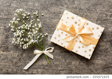 Gift or present box and flower gypsophila on light table top view. Greeting card. Flat lay style with copy space 105872835