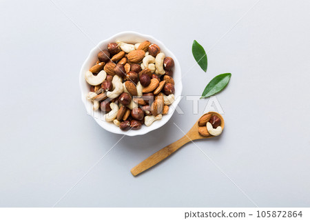 Assortment of nuts in wooden bowl on colored table. Cashew, hazelnuts, walnuts, almonds. Mix of nuts Top view with copy space 105872864
