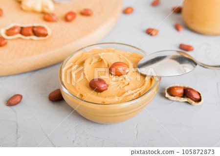 Bowl of peanut butter and peanuts on table background. top view with copy space. Creamy peanut pasta in small bowl Bowl of peanut butter and peanuts on table background. top view with copy space. Creamy peanut pasta in small bowl 105872873