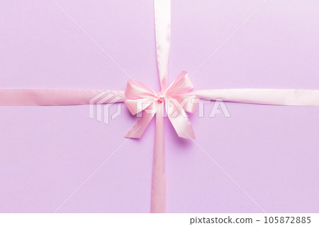 Top view of purple ribbon rolled and pink bow isolated on colored background. Flat lay with copy space Top view of purple ribbon rolled and pink bow isolated on colored background. Flat lay with copy space 105872885