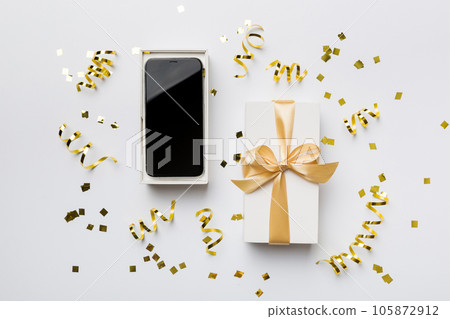 Opened gift box with gold ribbon and smartphone on color background, top view. Blank open box packaging mockup , Template for your design - branding mockup 105872912