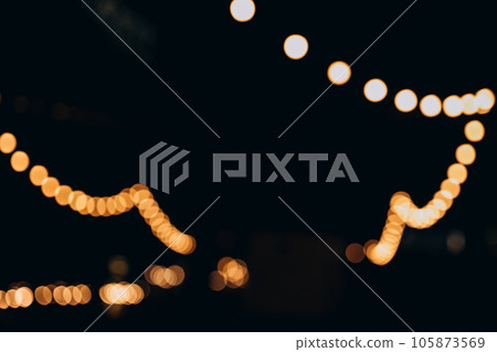Decorative outdoor string lights at night time, Defocused Background, night city life backdrop, party time with Yellow bokeh balls 105873569