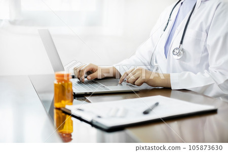 The female doctor sat and checked the patient's history and used a laptop to record patient information at the hospital. Medical concepts and interests 105873630