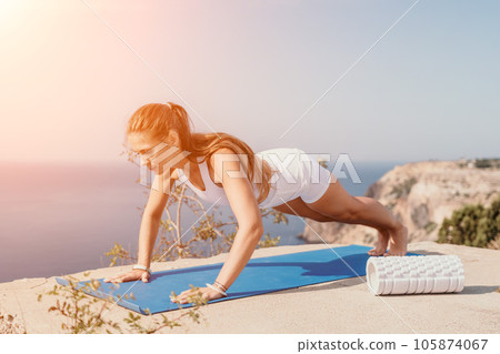 Fitness woman sea. Outdoor workout on yoga mat roller in park near to ocean beach. Female fitness pilates yoga routine concept. Healthy lifestyle. Happy fit woman exercising with rubber band in park. Fitness woman sea. Outdoor workout on yoga mat roller in park near to ocean beach. Female fitness pilates yoga routine concept. Healthy lifestyle. Happy fit woman exercising with rubber band in park. 105874067