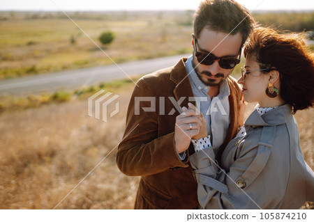 Stylish and loving couple enjoying each other outdoors. Stylish couple walking and hugging. 105874210