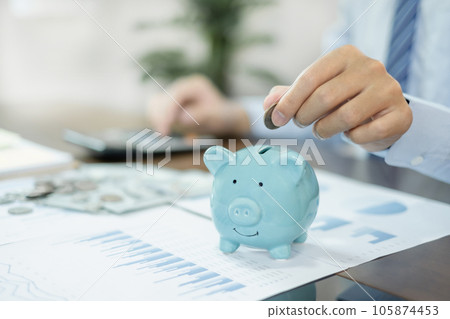 Hand putting coin into piggy bank. Saving money with coins steps into a successful growing business, and saves it for retirement. Retirement Savings concept Hand putting coin into piggy bank. Saving money with coins steps into a successful growing business, and saves it for retirement. Retirement Savings concept 105874453