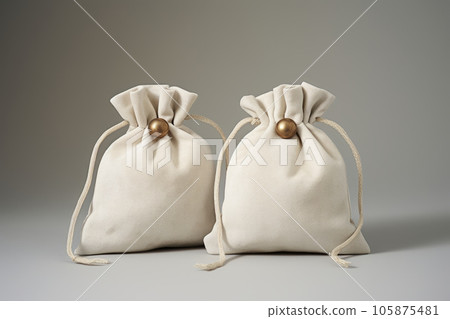 Beige silk fabric bags with laces for jewelry are on the table Beige silk fabric bags with laces for jewelry are on the table 105875481