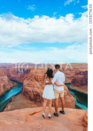 Happy couple on the edge of the cliff at Horseshoe Band Canyon in Paje, Arizona. Adventure and tourism concept. Beautiful nature in USA Happy couple on the edge of the cliff at Horseshoe Band Canyon in Paje, Arizona. Adventure and tourism concept. Beautiful nature in USA 105875630