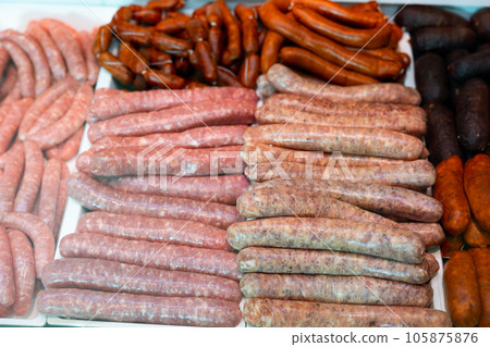 Different types of sausages laid out in showcase of butcher shop 105875876