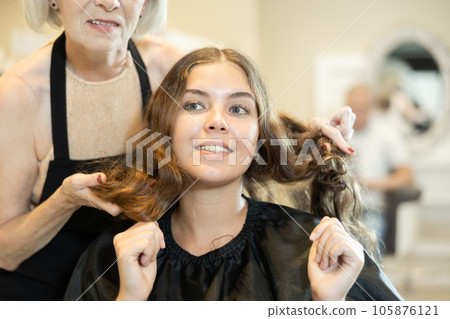 Cropped elderly woman hairdresser does discusses with girl customer length of hair, shape of haircut Cropped elderly woman hairdresser does discusses with girl customer length of hair, shape of haircut 105876121
