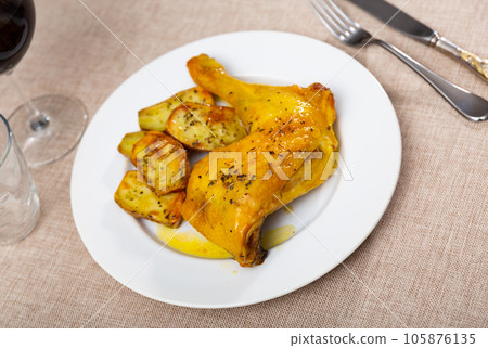 Fried chicken thigh seasoned with garlic in own juice and garnished with pieces of baked potatoes 105876135