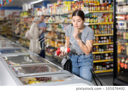 Young girl looking at foods in glass refrigerated display case 105876492