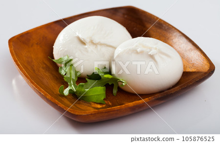Burrata italian white cheese and arugula leaf closeup Burrata italian white cheese and arugula leaf closeup 105876525