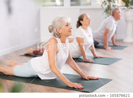 Mature women of different year practice yoga and Pilates in virabhadrasana pose in gym Mature women of different year practice yoga and Pilates in virabhadrasana pose in gym 105876621