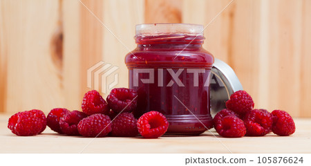 Sweet raspberry jam in jar and berries on wooden surface, nobody Sweet raspberry jam in jar and berries on wooden surface, nobody 105876624