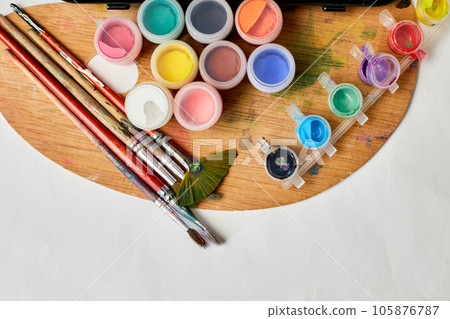 Flat lay of colorful paints, painting palette and brushes Flat lay of colorful paints, painting palette and brushes 105876787