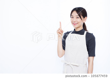 A housewife in her thirties who raises her index finger in front of a white background 105877459