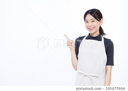 A housewife in her thirties who raises her index finger in front of a white background 105877604
