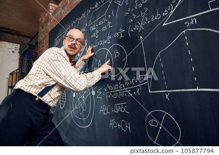 Emotional man, professor, scientist standing by blackboard with scientific formulas and calculations. Math, physics, chemistry lessons 105877794