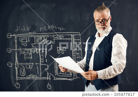 Stylish senior man, professional architect working with architectural design, making sketches on blackboard Stylish senior man, professional architect working with architectural design, making sketches on blackboard 105877817