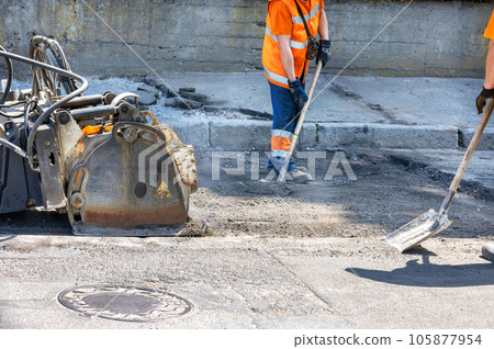 Milling of the old asphalt pavement with a powerful attachment of the cutter for the subsequent repair of the roadway. 105877954