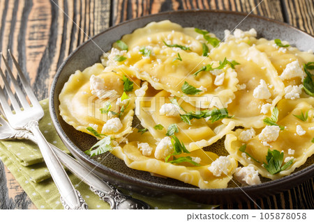 Ravioli mezzaluna pasta with goat cheese and herbs close-up in a plate. Horizontal Ravioli mezzaluna pasta with goat cheese and herbs close-up in a plate. Horizontal 105878058