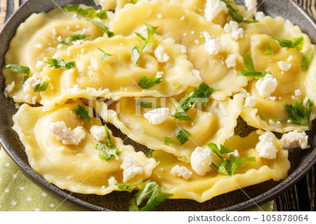 Homemade pasta mezzaluna stuffed with goat cheese and herbs close-up in a plate. Horizontal Homemade pasta mezzaluna stuffed with goat cheese and herbs close-up in a plate. Horizontal 105878064