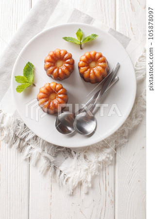 Caneles de bordeaux traditional French sweet dessert close-up in a plate. Vertical top view Caneles de bordeaux traditional French sweet dessert close-up in a plate. Vertical top view 105878097