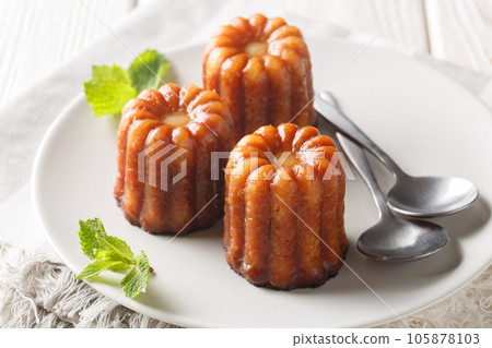 French Canele is a delicious pastry with a vanilla custard filling and a sweet caramelized crust close-up in a plate. Horizontal French Canele is a delicious pastry with a vanilla custard filling and a sweet caramelized crust close-up in a plate. Horizontal 105878103