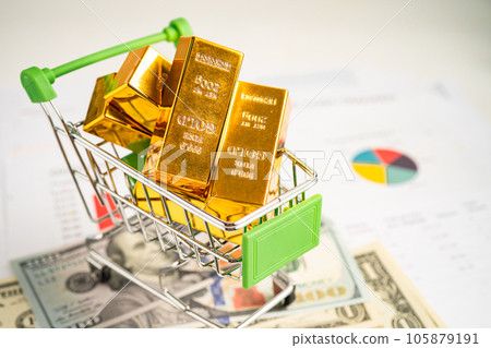 Gold bar in shopping cart on US dollar banknotes money and graph, economy finance exchange trade investment concept. Gold bar in shopping cart on US dollar banknotes money and graph, economy finance exchange trade investment concept. 105879191
