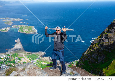 Relaxed happy hiker enjoys stunning views on Reinebringen peaks of Lofoten islands, fjords, Norway Relaxed happy hiker enjoys stunning views on Reinebringen peaks of Lofoten islands, fjords, Norway 105879965