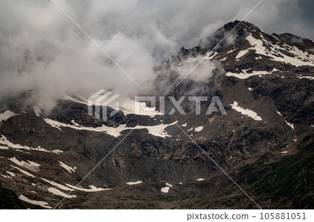 gloomy atmospheric rocks, dark mountains covered with clouds and puffs of fog. Mountain peak of snow-capped mountains, beautiful panorama of mountains. dark high rocks 105881051