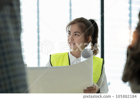 Young architect and engineer colleague workers working discussion, meeting and analyzing blueprint at construction site 105882184