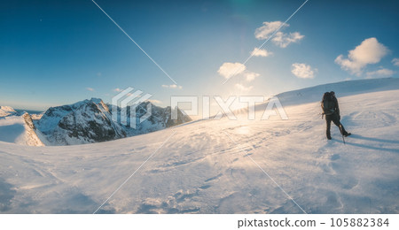 Mountaineer climbing to the top of snowy mountain and sunset shining in winter 105882384