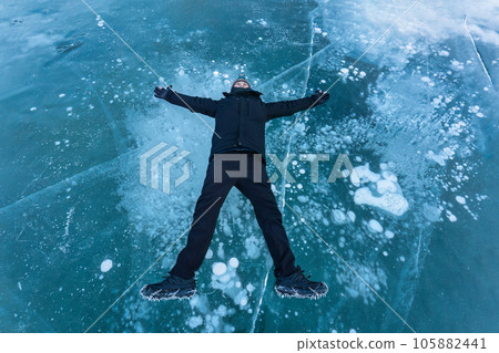 Asian male tourist lying and enjoying on frozen lake with natural bubble Asian male tourist lying and enjoying on frozen lake with natural bubble 105882441