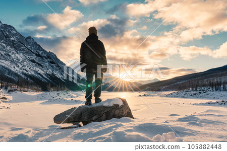 Solo young adventurer standing on snow covered lake with sunrise over Medicine Lake in morning on winter at Jasper national park 105882448