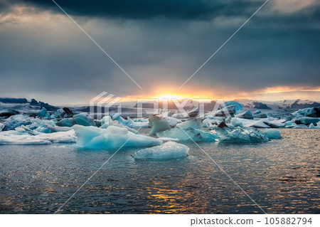 Sunset shining over Jokulsarlon glacier lagoon with blue iceberg at Iceland Sunset shining over Jokulsarlon glacier lagoon with blue iceberg at Iceland 105882794