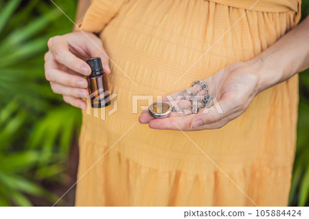 pregnant woman after 40 demonstrating the use of an aroma pendant, combining style and aromatherapy during her pregnancy journey pregnant woman after 40 demonstrating the use of an aroma pendant, combining style and aromatherapy during her pregnancy journey 105884424