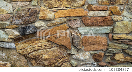 Fragment of a natural stone wall as a background or texture. The structure of the stone wall. Old castle stone wall texture 105884857