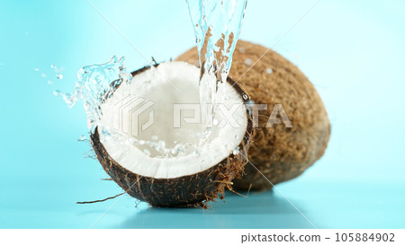 Cracked coconut with splashing water on blue background 105884902