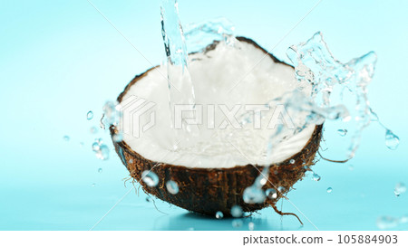 Cracked coconut with splashing water on blue background 105884903