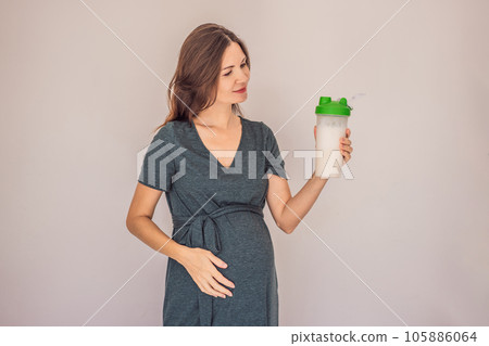 Energetic and fit pregnant woman after 40 enjoying a protein shake for a nourishing boost during her pregnancy journey. Embracing health and wellness for a thriving baby and mom 105886064