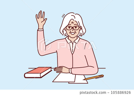Happy elderly woman student sits at school desk with book and raises hand up wanting to ask question Happy elderly woman student sits at school desk with book and raises hand up wanting to ask question 105886926